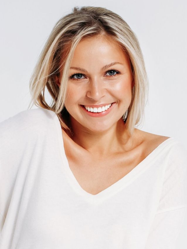 Smiling woman in white top, cheerful expression.