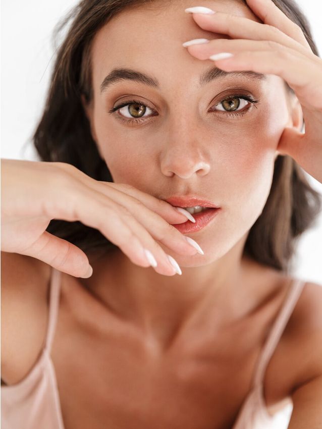Woman posing with hands near face, natural makeup.