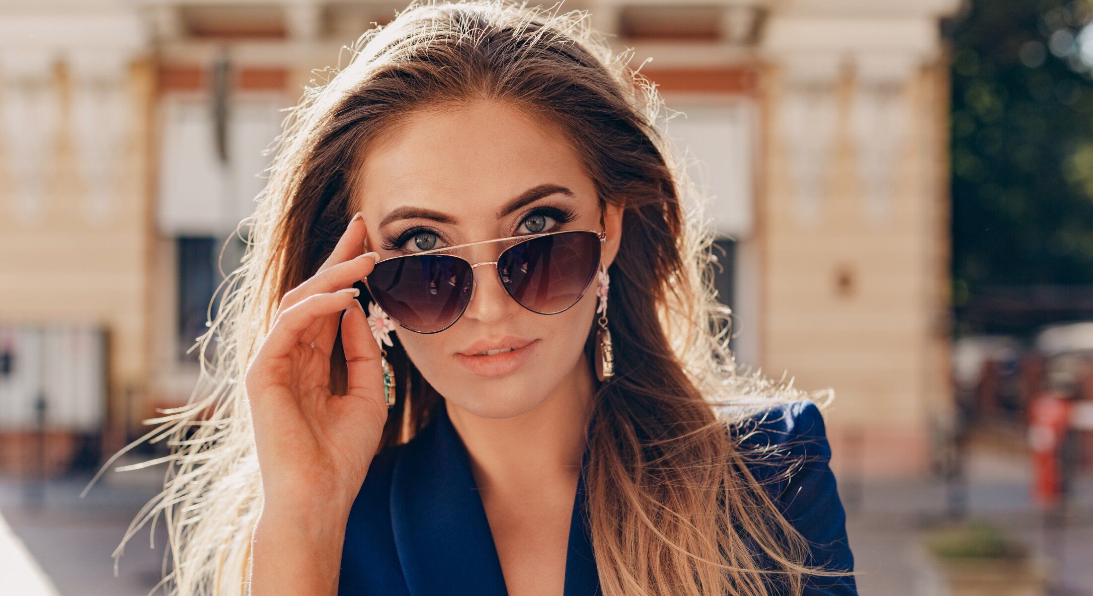 Woman in sunglasses with flowing hair outdoors.